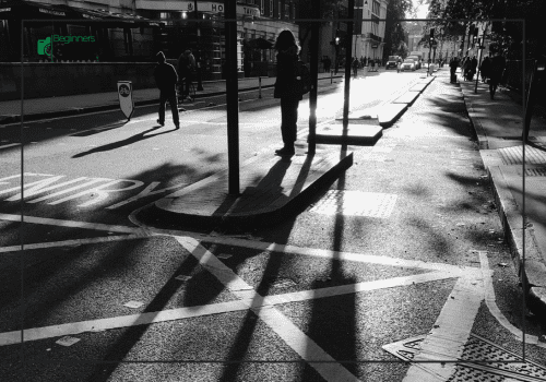 Black & White Street Photography – Shadows and Light in the City Black and white street photo showing long shadows of people walking in sunlight.