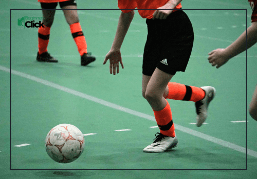 Close-up of indoor football players in action, focusing on the ball and player’s legs.