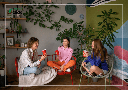 Three young women sitting indoors with red cups, enjoying conversation in a cozy living room with plants.
