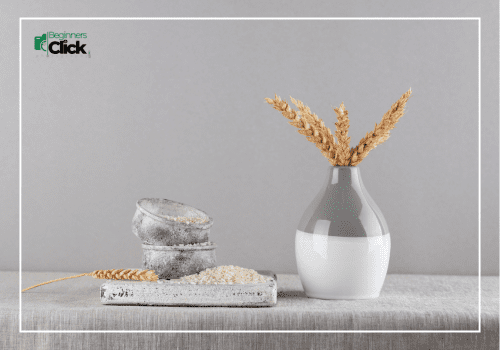 Minimalist still life with a modern vase holding wheat stalks and rustic stone elements on a neutral background.
