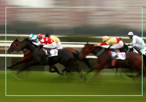 The Final Stretch A group of jockeys riding racehorses at high speed during a horse race, with motion blur capturing the intensity and movement on a grassy racetrack.