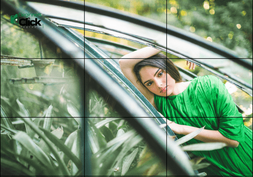 Framed by Nature: A Creative Portrait in Green A woman in a green dress leaning on the door of an old car surrounded by lush greenery, framed with diagonal lines and natural light.