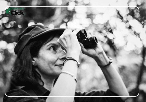 Understanding Exposure Triangle – Light, Shutter, and Sensitivity A woman observing through binoculars in a forest, shown in black and white, symbolizing focus and exposure balance in photography.