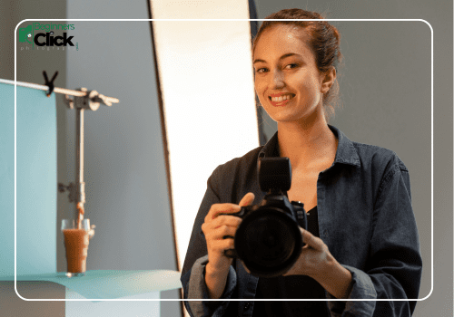 Beginner’s Studio Setup – Lighting & Product Focus A smiling female photographer holding a DSLR camera in a studio setup with lighting equipment and a product on display.