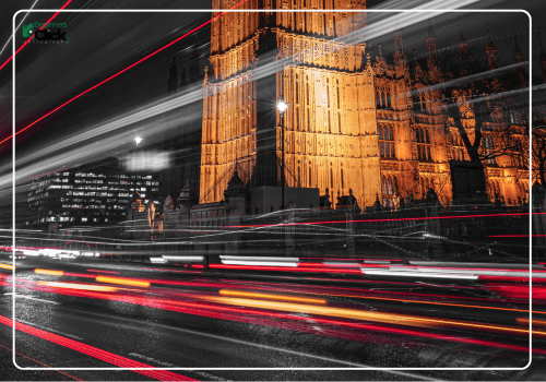 Night Traffic Light Trails – Cityscape in Motion Long exposure photo of traffic light trails in front of a brightly lit Gothic building at night.