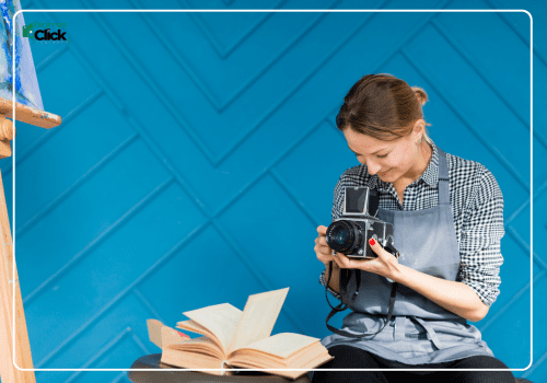 Learning Photography from Scratch A person learning photography from scratch, holding a camera while sitting in a cozy environment with an open book on the table.