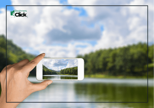 Don’t Zoom, Just Move – Smartphone Landscape Photography Hand holding a smartphone to capture a landscape photo of a lake and forest under a cloudy sky.