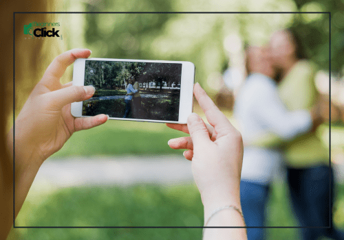 Play Around and Have Fun A person taking a photo with a smartphone of two people hugging outdoors in a park.