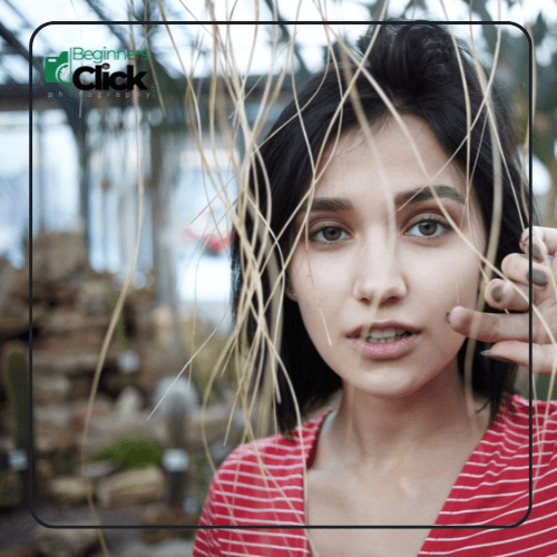 Portrait with Short Focal Length A close-up shot of a woman captured with a short focal length lens, with plants framing her face and a blurred background.